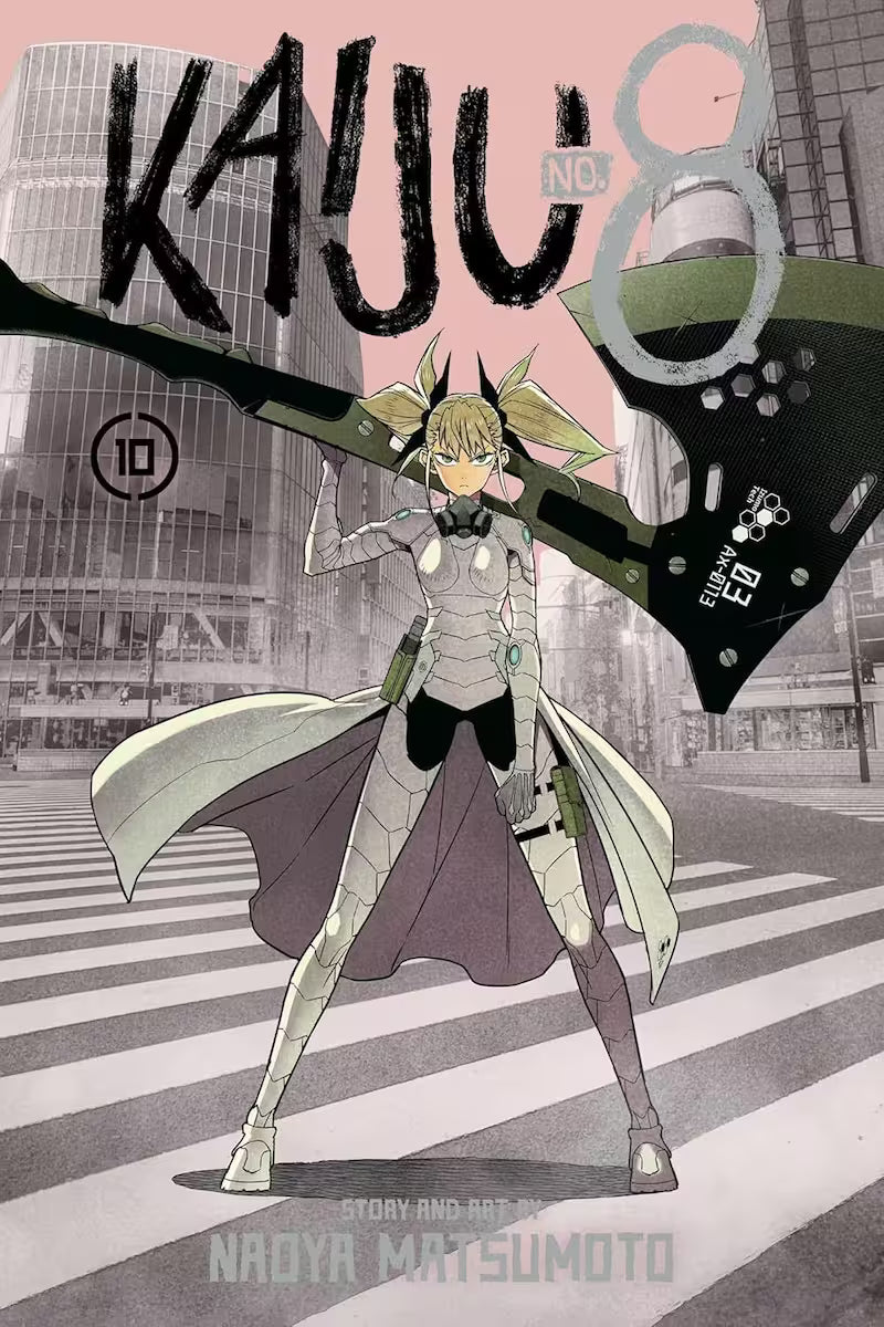 Manga-forside af Kaiju No. 8 bind 10 med Kikoru Shinomiya i fuld kampdragt, stående midt på en tom storby-krydspassage med et enormt våben hvilende over skulderen. Baggrunden er gråtonet, mens hun selv står frem i lyse, skarpe farver.